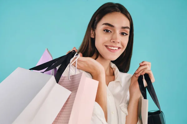 Porträt eines hübschen lächelnden Mädchens mit Einkaufstüten, das freudig in die Kamera über bunten Hintergrund blickt — Stockfoto