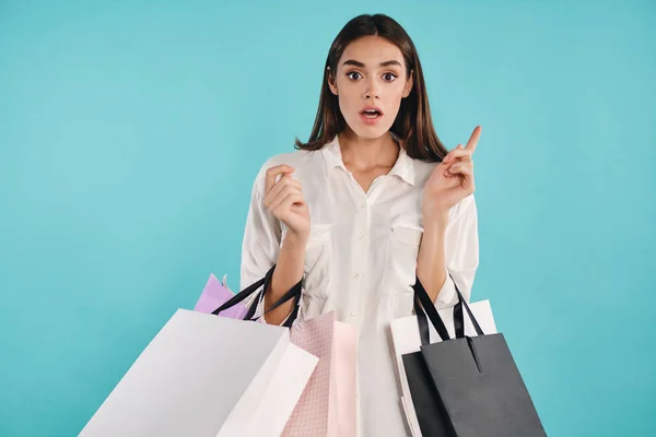 Vonzó alkalmi lány bevásárló táskák csodálatosan nézett a kamerába, amelynek ötlete át színes háttér — Stock Fotó