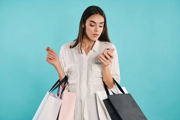 Attraktive lässige Mädchen mit Einkaufstaschen selbstbewusst mit Handy über bunten Hintergrund — Stockfoto