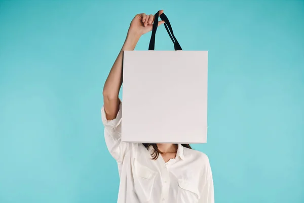 Menina casual atraente cobrindo rosto com saco de compras sobre fundo colorido — Fotografia de Stock