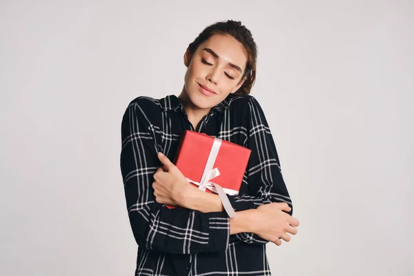 Mooi casual meisje dromerig knuffelen gift box over grijze achtergrond — Stockfoto