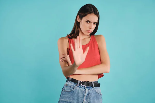 Angry casual girl  sadly looking in camera showing stop gesture over colorful background — Stock Photo, Image