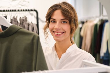 Genç, güzel, şık bir kadın kameraya bakıp modern bir galeride çalışıyor. 