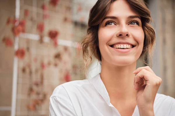 Muotokuva nuori kaunis hymyilevä nainen iloisesti katselee pois työpajassa — kuvapankkivalokuva