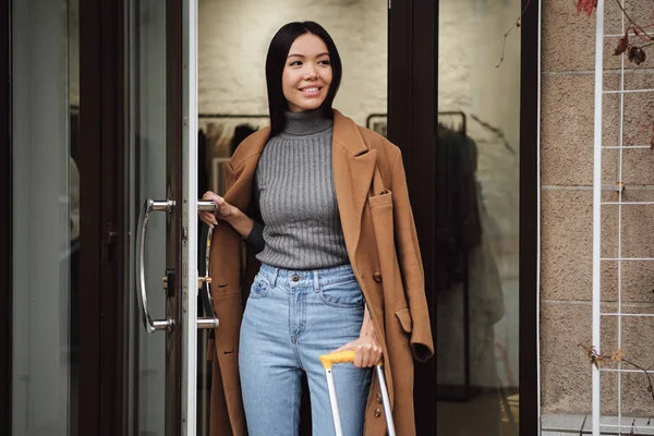 Красивая случайная азиатская девушка счастливо смотрит в сторону уходя из модного магазина — стоковое фото