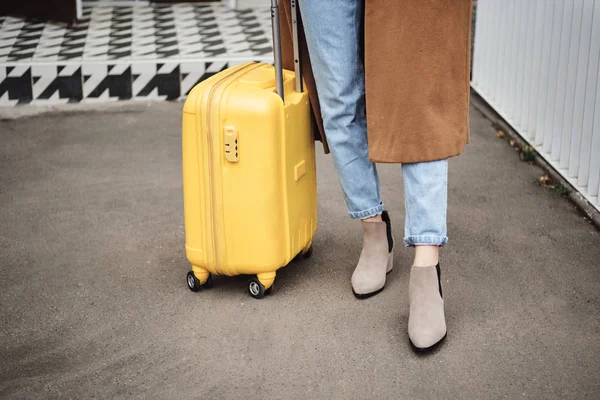 Close up stylish girl in coat standing with yellow suitcase on street — Stock Photo, Image