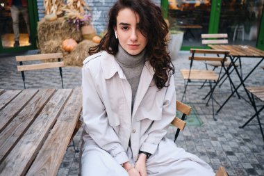 Trençkotlu çekici esmer kız rüyasında caddedeki kafede kameraya bakıyordu.