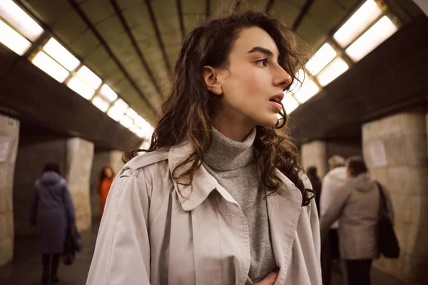 Портрет довольно случайная девушка в плаще вдумчиво глядя в сторону на станции метро — стоковое фото