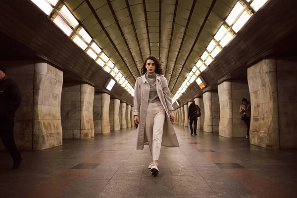 Attraktives lässiges Mädchen im Trenchcoat läuft selbstbewusst durch U-Bahn-Station — Stockfoto