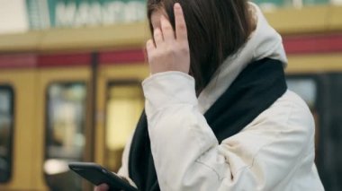 Açık havada cep telefonu kullanarak atkısını takmış sıradan bir genç kızın portresi.