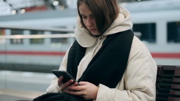 Střední Záběr Ležérní Dívka Bundě Šátkem Zamyšleně Pomocí Mobilu Čeká — Stock video