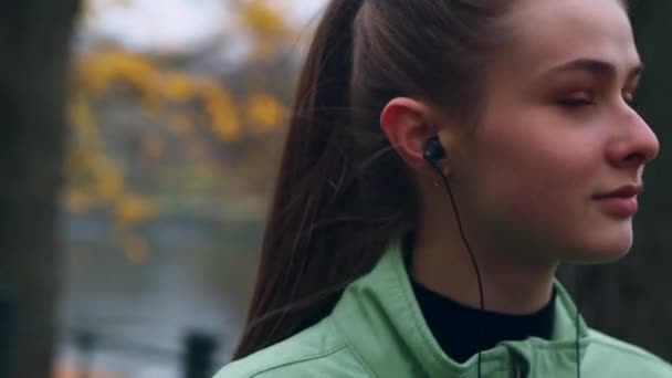 공원인 리버사이드에서 달리고 이어폰을 속에서 아름다운 스포츠 소녀의 — 비디오