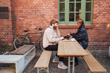 Caddedeki kafede kahve molası sırasında laptopta mutlu bir şekilde çalışan genç bir çift.