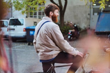 Şehrin sokaklarında bisiklet süren çekici genç adamın arka manzarası