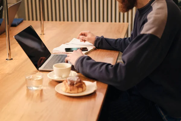 Primer plano joven que trabaja en el ordenador portátil durante la pausa para el café en la cafetería — Foto de Stock