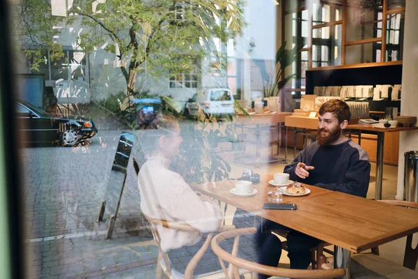 Joven hermosa pareja felizmente hablando durante el descanso de café en acogedora cafetería — Foto de Stock