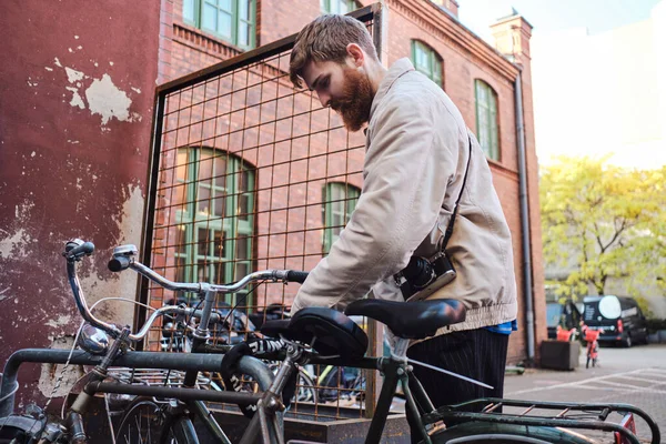 Young stylish bearded man parking his bicycle on city street — Stock Photo, Image