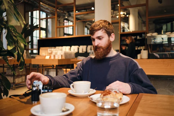 Giovane bell'uomo barbuto avendo pausa caffè in caffè moderno — Foto Stock