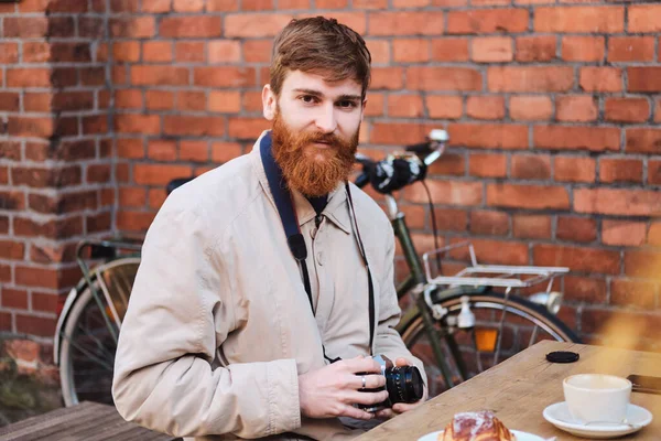 Young attractive casual photographer intently looking in camera in cafe outdoor — 스톡 사진