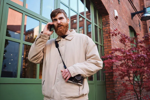 Young casual bearded man angrily talking on cellphone outdoor — 스톡 사진