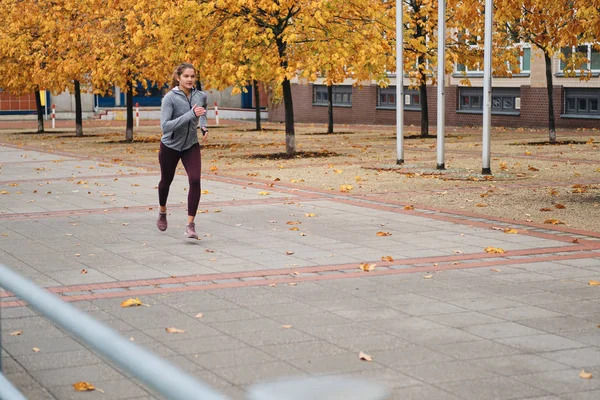 Atrakcyjna dziewczyna w sportowym stroju biegająca po pustych ulicach miasta — Zdjęcie stockowe