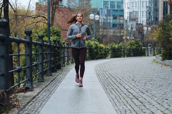 Atrakcyjna sportowa dziewczyna biegnie przez pustą ulicę miasta — Zdjęcie stockowe