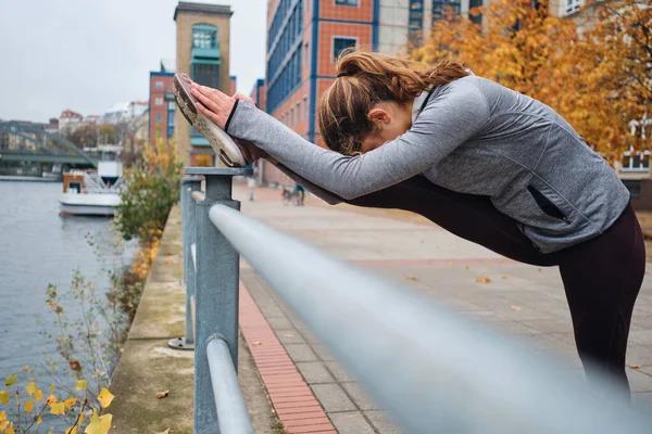 Młoda atrakcyjna sportowa dziewczyna rozciągająca się podczas treningu na pustej ulicy miasta — Zdjęcie stockowe