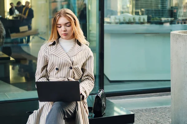 Młoda stylowa bizneswoman pewnie pracuje na laptopie na ulicy miejskiej — Zdjęcie stockowe