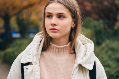 Güzel sıradan bir kız düşünceli bir şekilde dışarı bakıyor. 