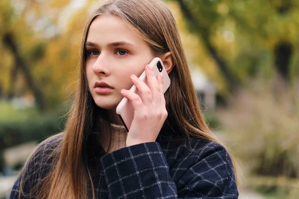 Muotokuva houkutteleva vakava tyttö puhuu matkapuhelin ulkona — kuvapankkivalokuva