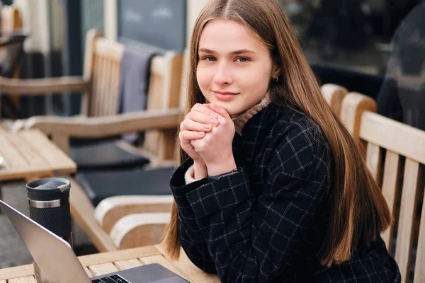 Pretty smiling girl happily looking in camera resting alone in cozy street cafe — Stock Photo, Image