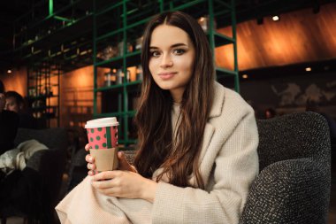 Güzel esmer kız rüyasında kameraya bakıyor modern kafede kahve içiyor.