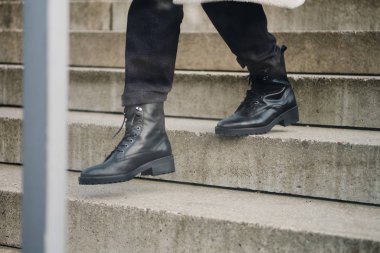 Siyah çizmeli genç bayanı kapatın. Merdivenlerden aşağı iniyor.