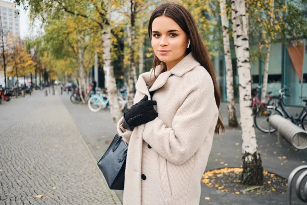 Schöne brünette Mädchen im Mantel verträumt Blick in die Kamera auf der Straße der Stadt — Stockfoto