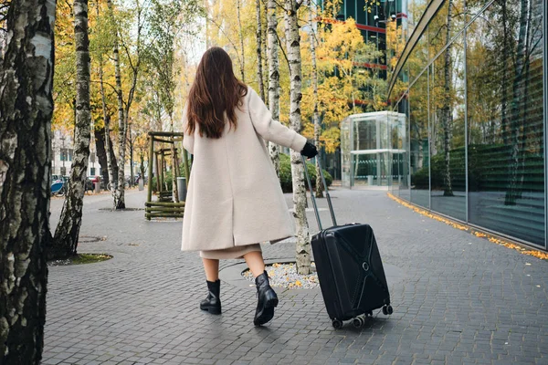 Επιστροφή άποψη του όμορφη κομψή μελαχρινή κοπέλα περπάτημα γύρω από το δρόμο της πόλης με βαλίτσα — Φωτογραφία Αρχείου