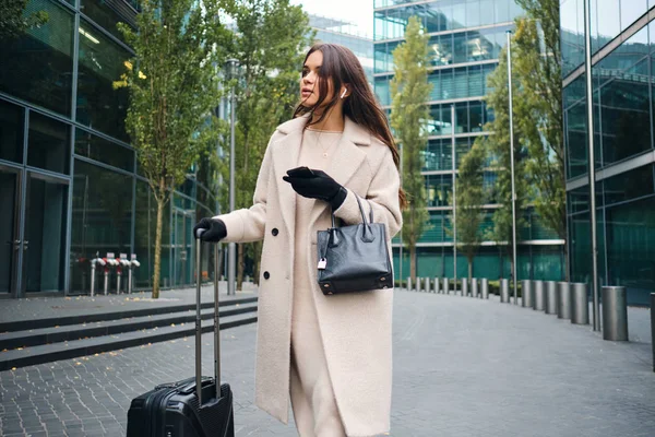 Schöne stilvolle Geschäftsfrau, die mit Koffer durch die Stadt läuft — Stockfoto