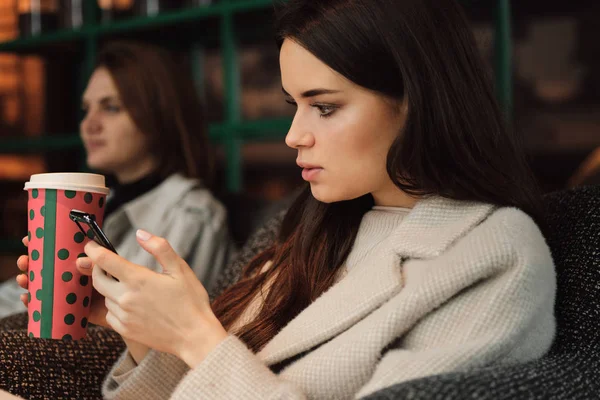 Portret van jonge zakenvrouw met koffie intensief gebruik van mobiele telefoon in cefe — Stockfoto