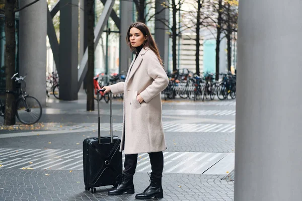 Schöne stilvolle Brünette Mädchen steht auf der Straße der Stadt mit kleinem Koffer — Stockfoto
