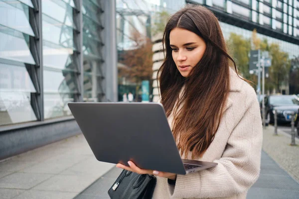 Jovem mulher de negócios atraente trabalhando intensamente no laptop na rua da cidade — Fotografia de Stock