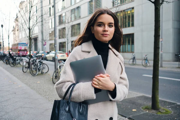 Młoda stylowa bizneswoman z laptopem pewnie przechadza się ulicą miasta — Zdjęcie stockowe