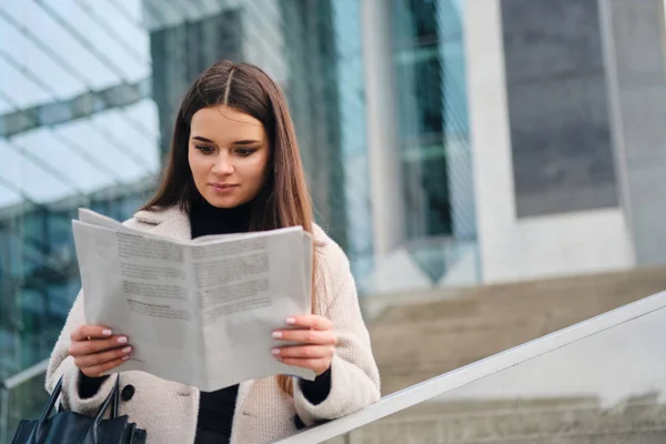 Vakker, stilfull forretningskvinne som leste en avis i sentrum – stockfoto