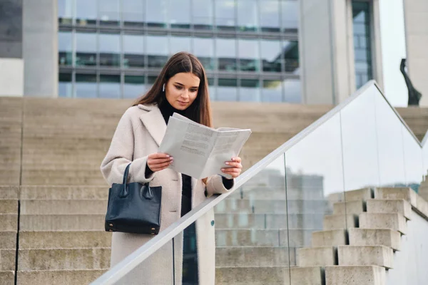 Attraktive stylische Geschäftsfrau mit Handtasche liest Zeitung in der Innenstadt — Stockfoto