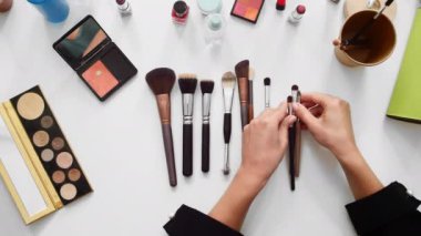Top view shot of close up beauty blogger showing different brushes and beauty products in make-up tutorial video