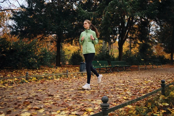 Piękna sportowa dziewczyna troskliwie biegając po przytulnym jesiennym parku sam — Zdjęcie stockowe