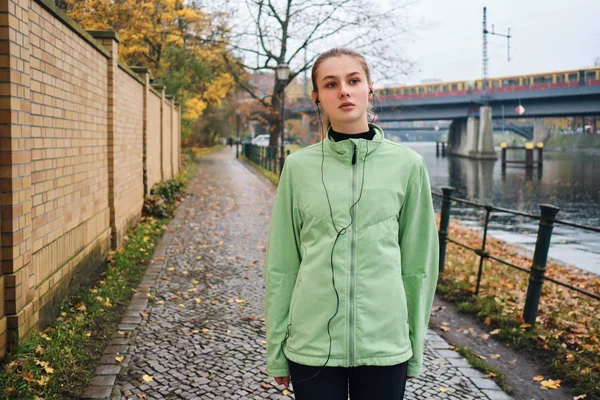 Attraktives sportliches Mädchen hört nach Lauf im Herbst im Stadtpark Musik in Kopfhörern — Stockfoto