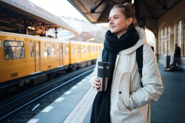 Oldukça sıradan bir turist kız metro istasyonunda bekleyen bir trende mutlu mesut duruyor.