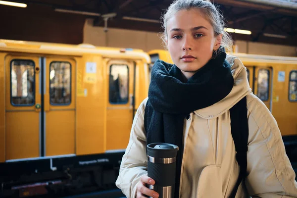 Piękny casual turysta dziewczyna na platformie uważnie patrząc w kamerę czeka pociąg w stacji metra — Zdjęcie stockowe