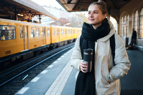 Menina turística casual atraente em pé na plataforma de trem de espera sonhadoramente na estação de metro — Fotografia de Stock