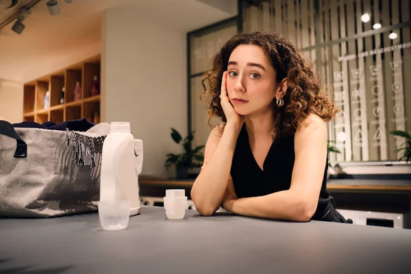 Mooi brunette meisje bedachtzaam kijken in camera wachten wassen in self-service wasserij — Stockfoto