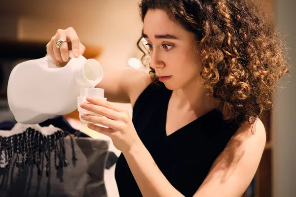 Ritratto di ragazza pensosa che lava i vestiti con detergente nella moderna lavanderia self-service — Foto Stock